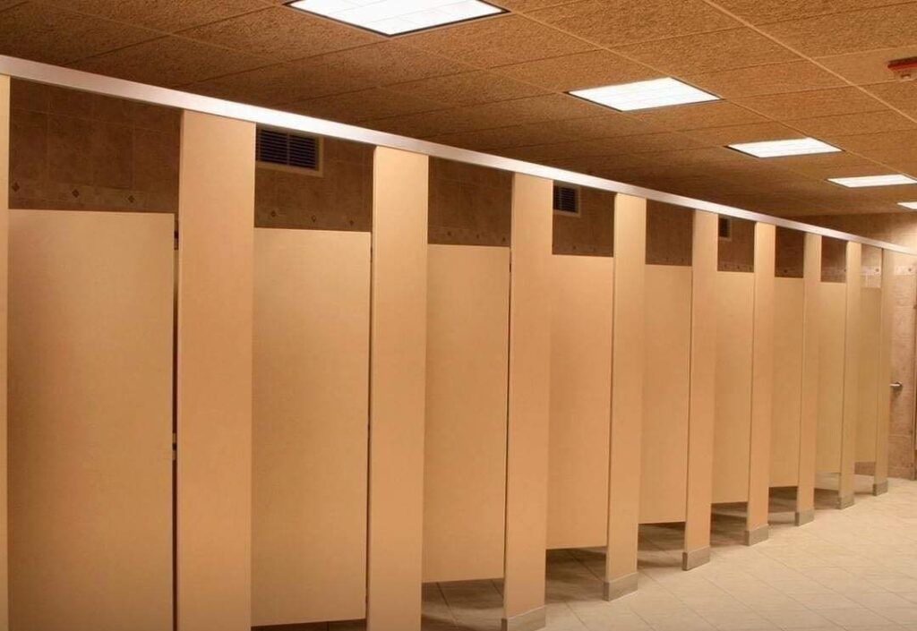 Why do public bathroom doors not reach the floor?